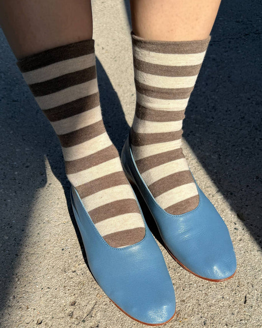 Striped socks and blue shoes on a concrete surface