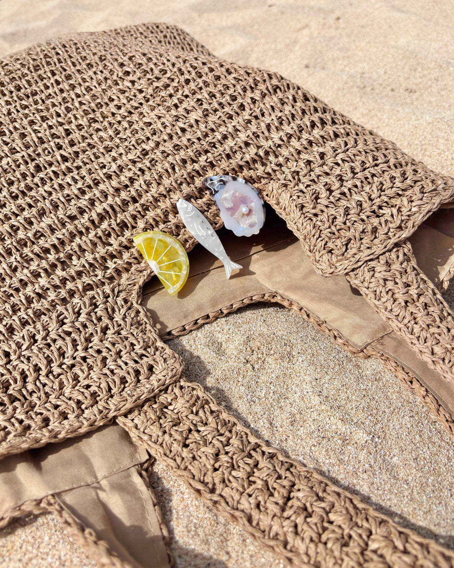 Brown woven mat with a lemon wedge and small figurine on a sandy surface