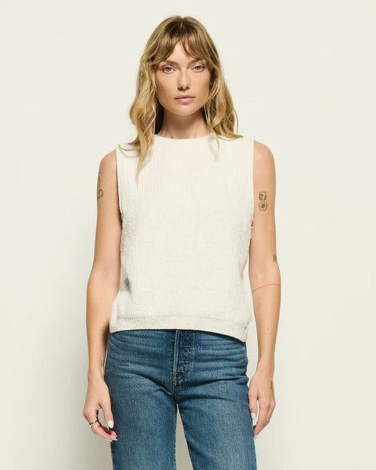 Model wearing the Nation Eliza Sweater Tank with jeans standing in front of a white wall.