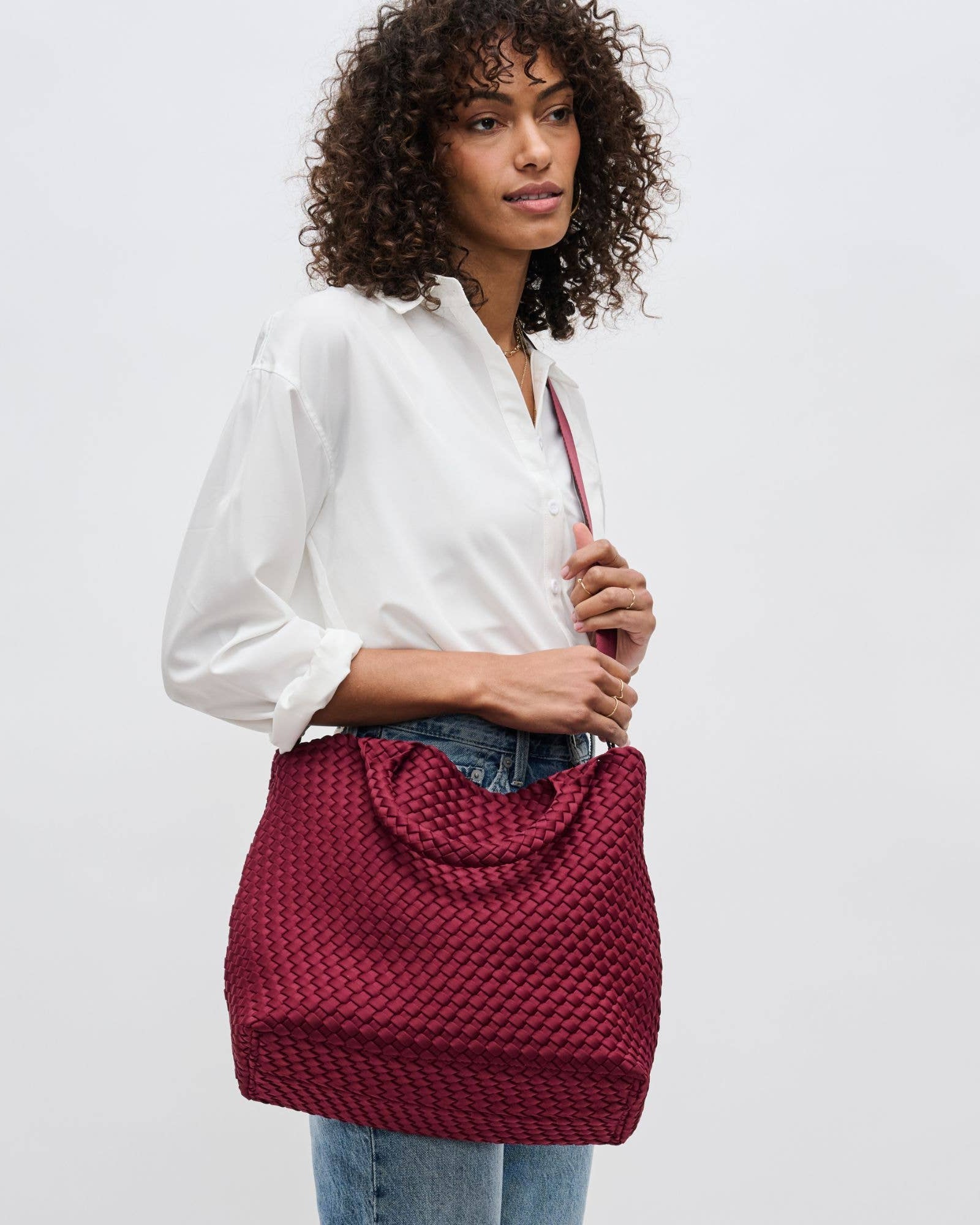 Woman holding a red textured handbag against a plain background