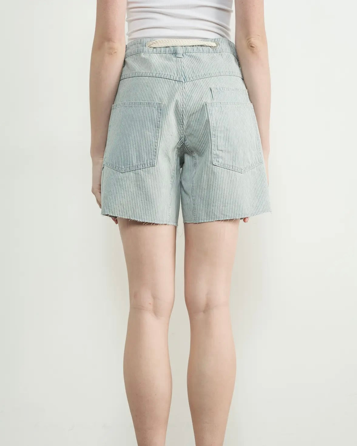 Model is wearing Aaron and Amber Vintage Washed Barrel Denim Shorts with a white top on a white background