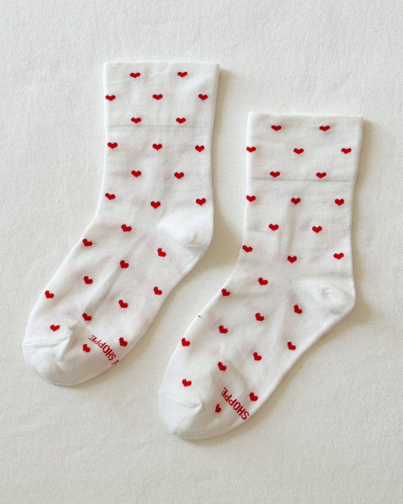 White socks with red heart patterns on a light gray background