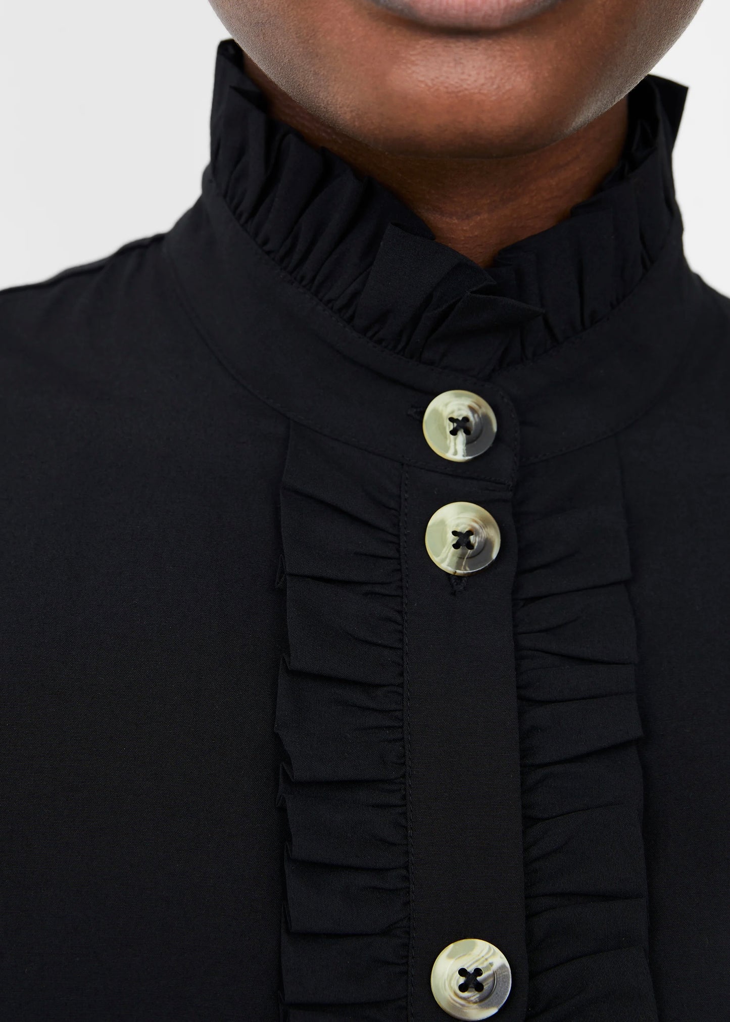 Close up of button and ruffle detail on the French Connection Eva Poplin Playsuit in black.