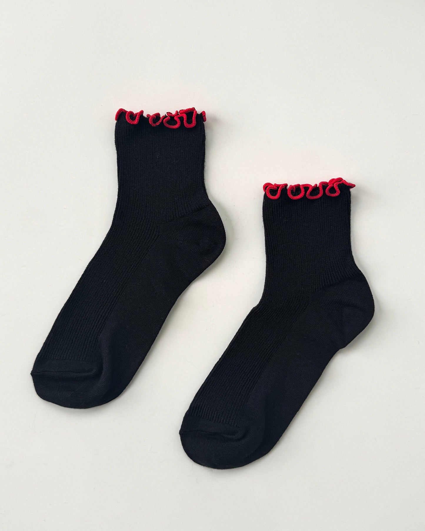 Pair of black socks with red trim on a light gray background