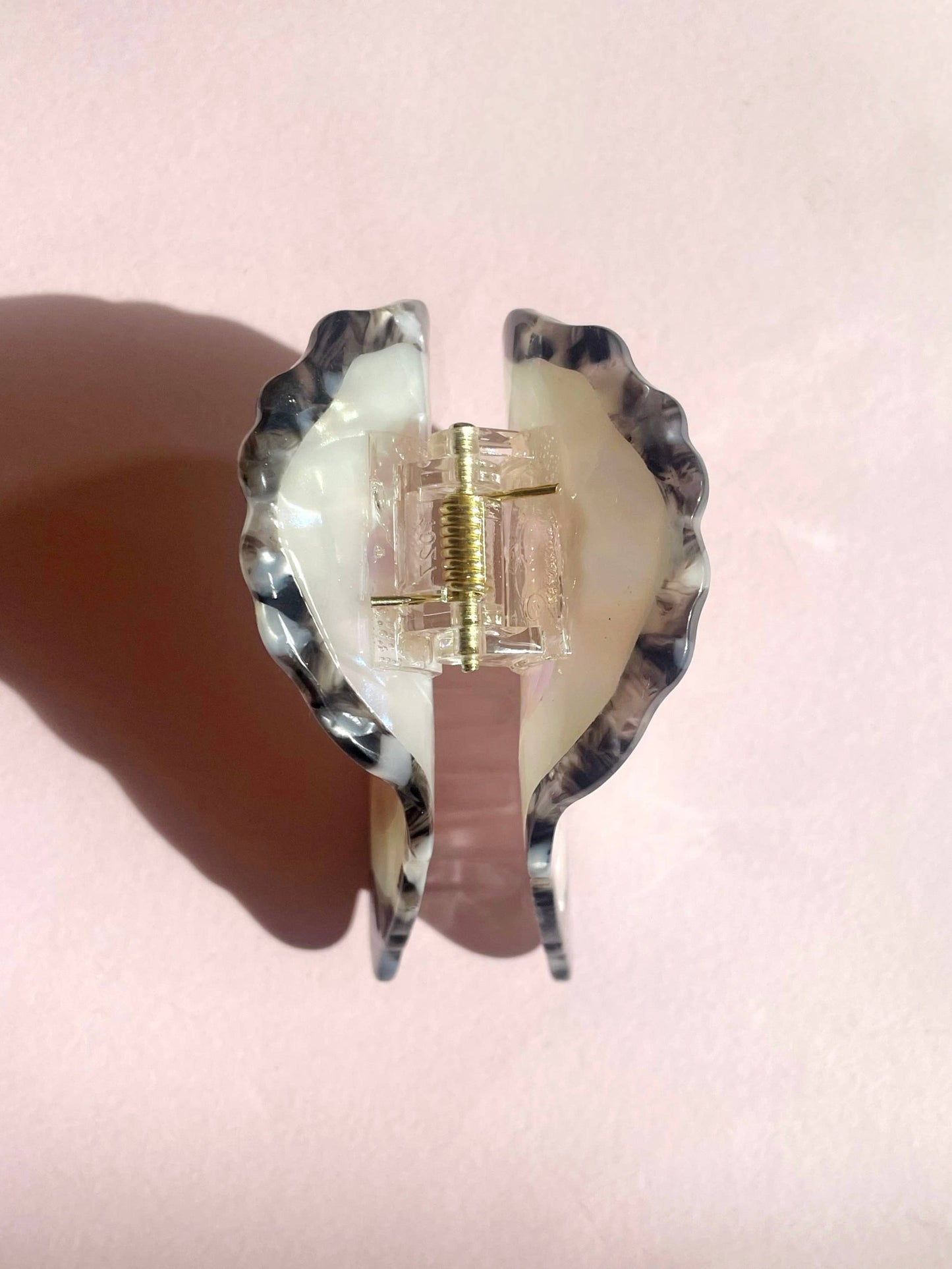 Back view of an oyster hair clip on a pink background