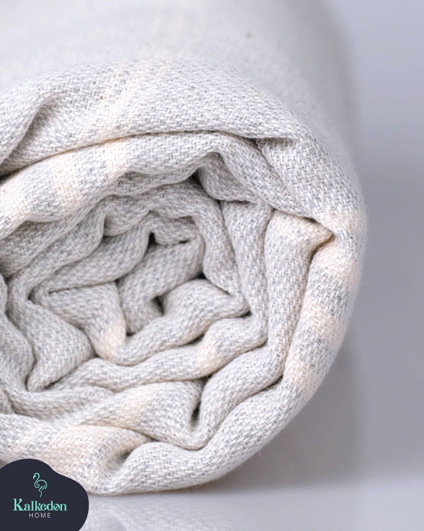 Rolled-up white blanket with a soft texture on a light gray background, featuring the Kallikuden brand.