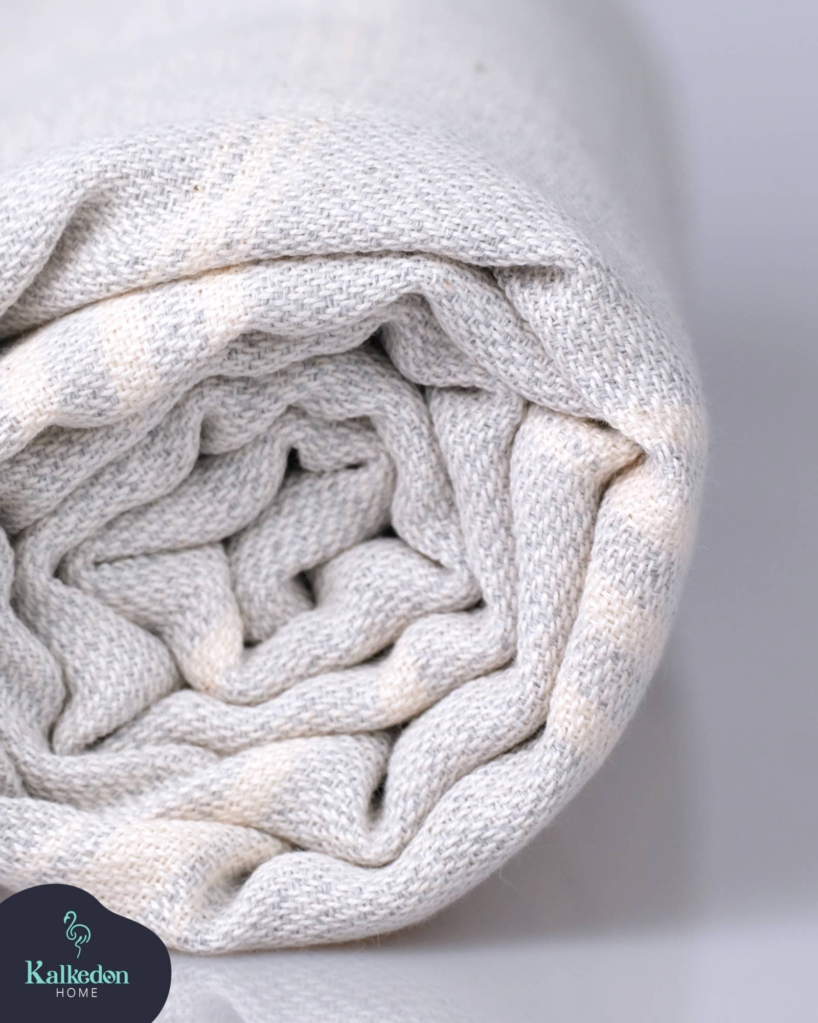 Rolled-up white blanket with a soft texture on a light gray background, featuring the Kallikuden brand.