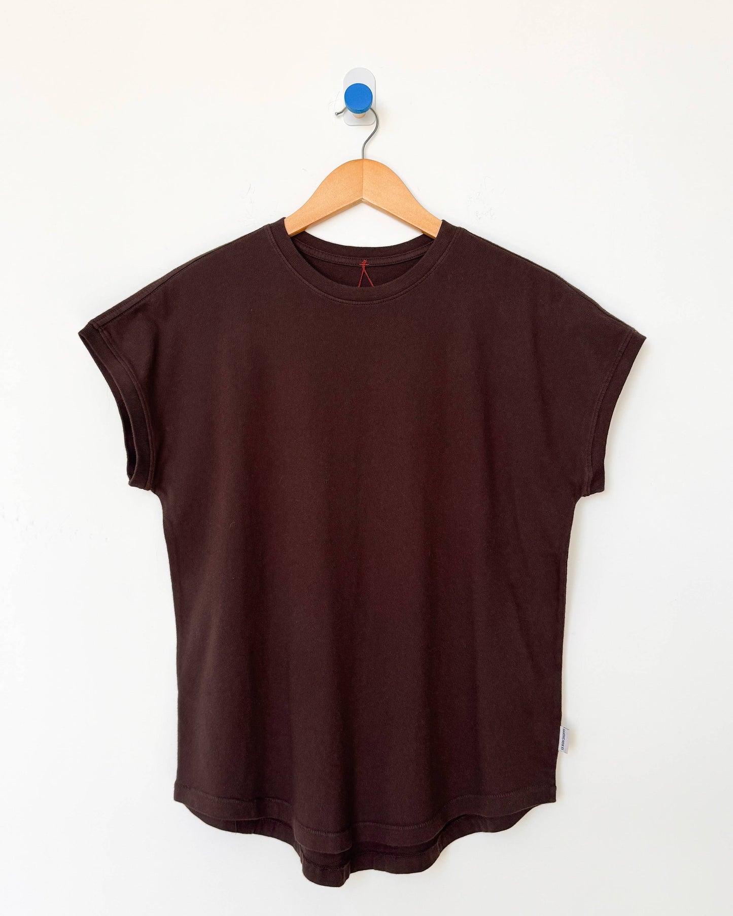 Brown sleeveless top on a wooden hanger against a white background