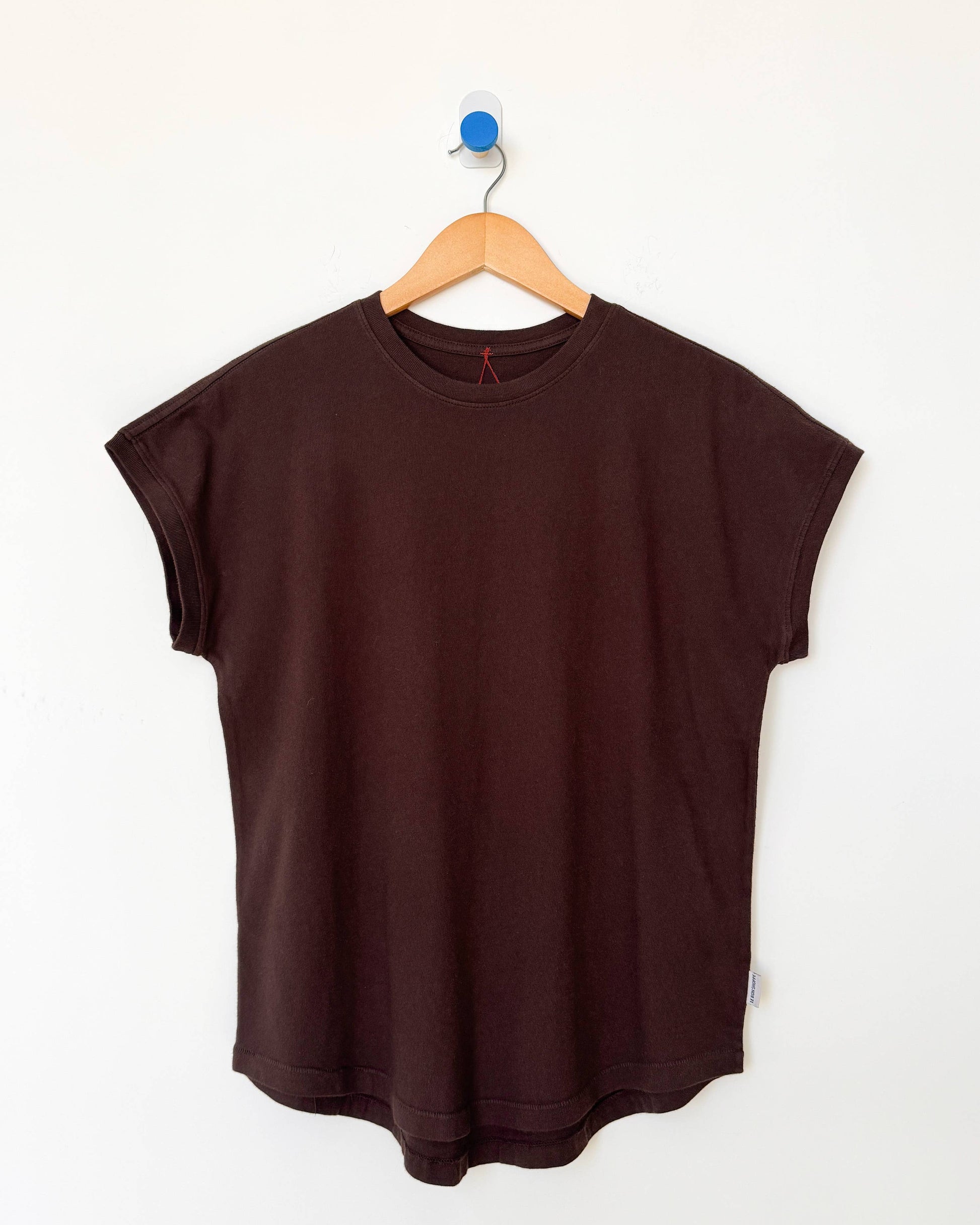 Brown sleeveless top on a wooden hanger against a white background