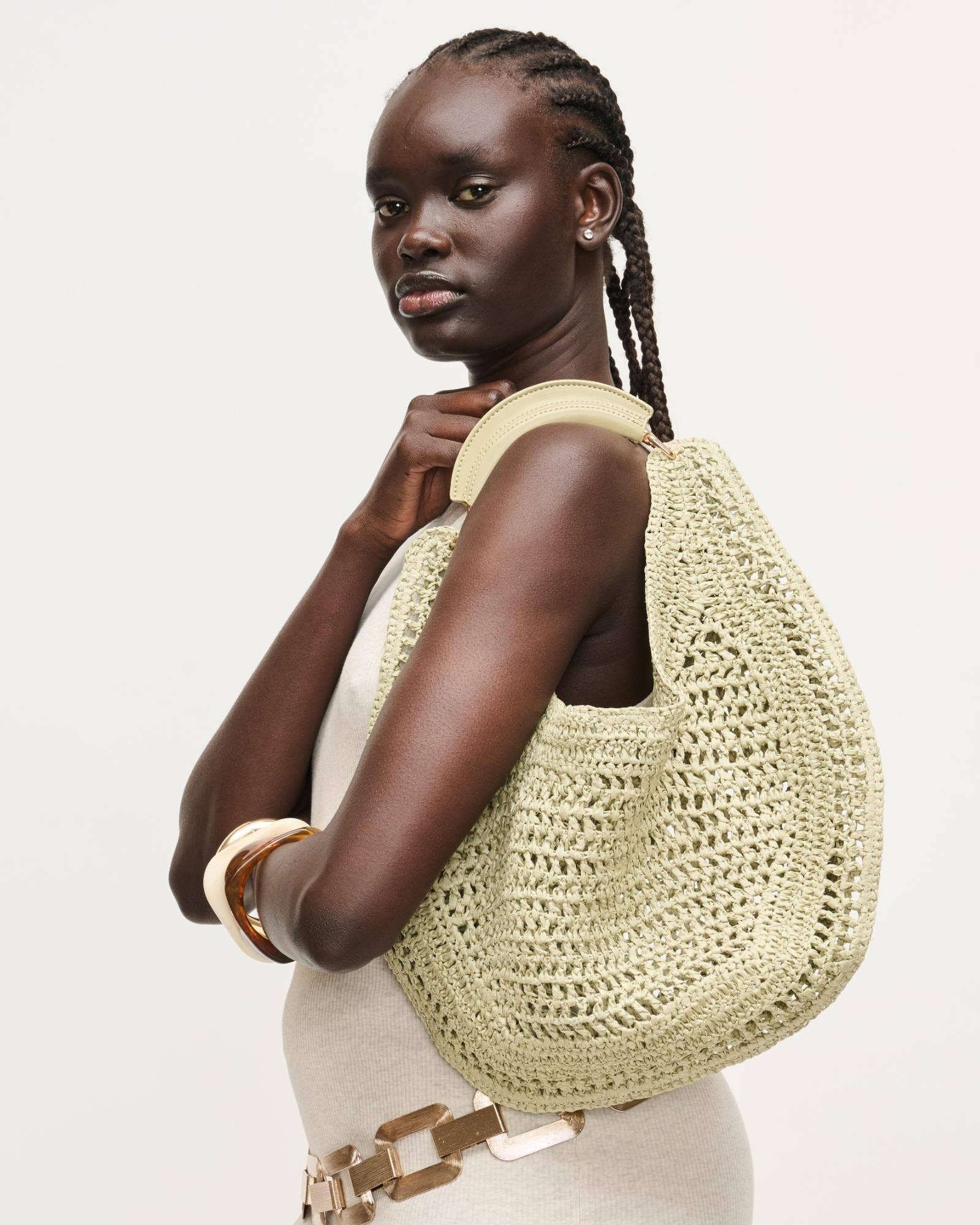 Woman holding a beige woven handbag against a plain background
