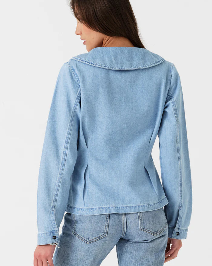 Woman wearing a light blue denim jacket and jeans on a white background