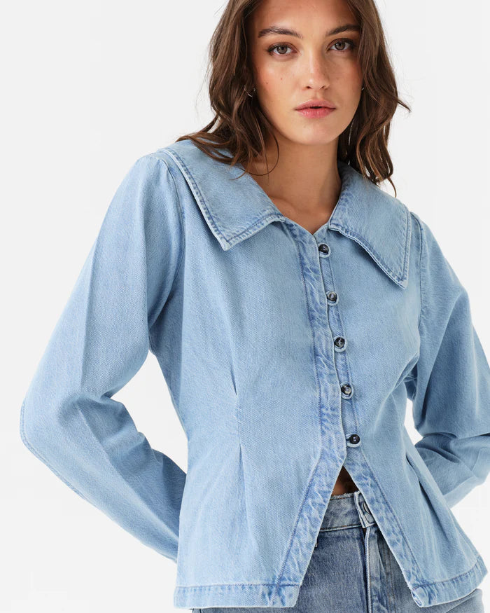 Woman wearing a light blue denim jacket on a white background