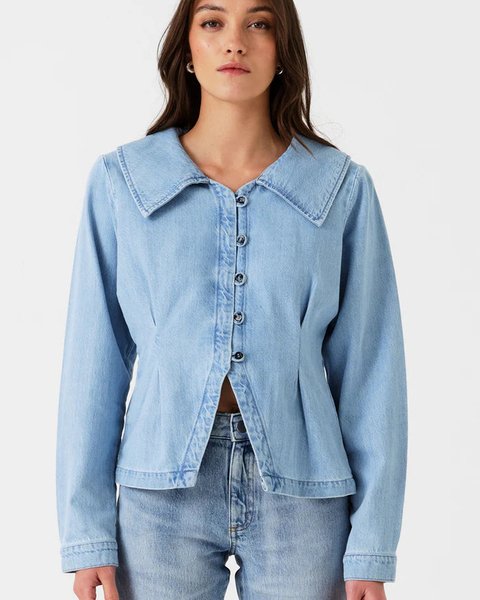 Woman wearing a light blue denim jacket and jeans on a white background