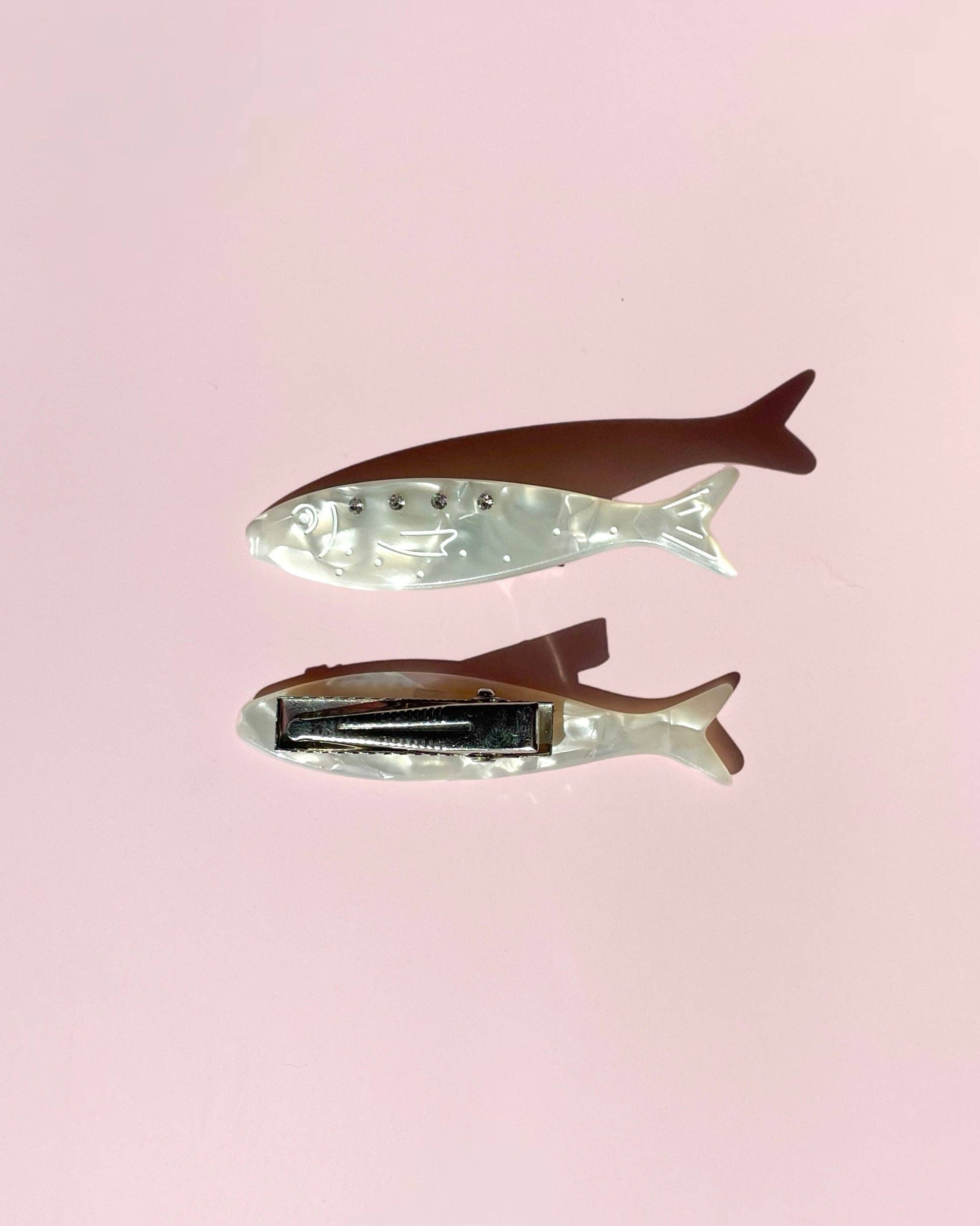 Two fish-shaped hair clips on a pink background