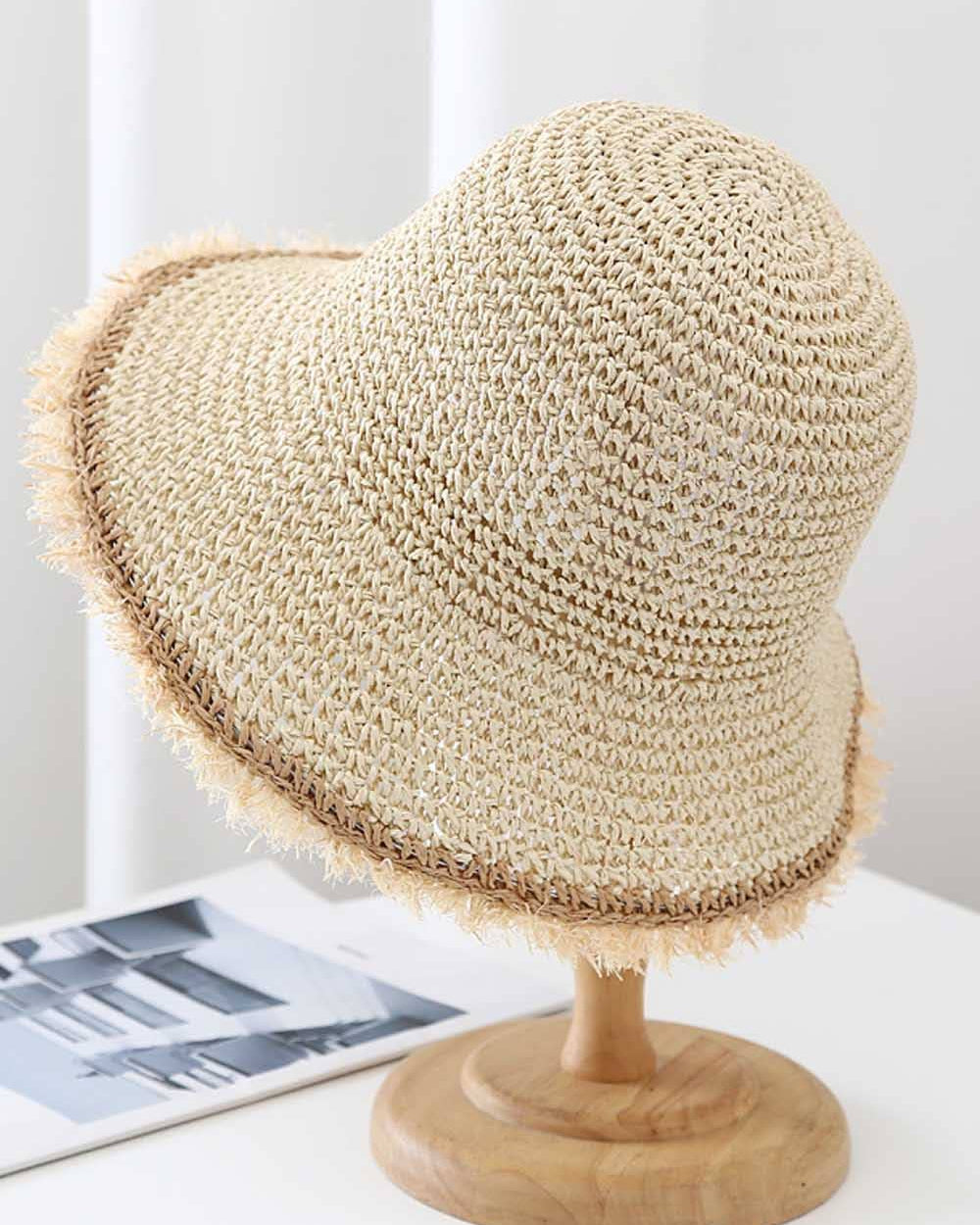 Beige straw hat on a wooden stand with a light gray background