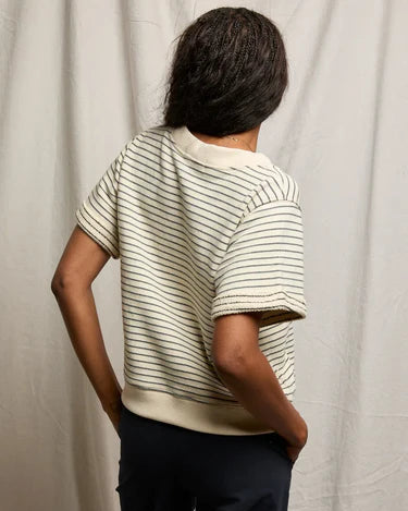 Person wearing a striped shirt and dark pants against a plain background