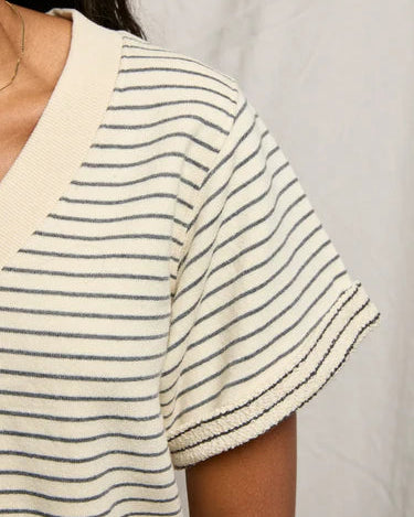 Close-up of a person wearing a white t-shirt with thin black stripes on a plain background