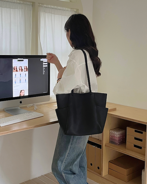 Person using a computer at a desk with a black tote bag.