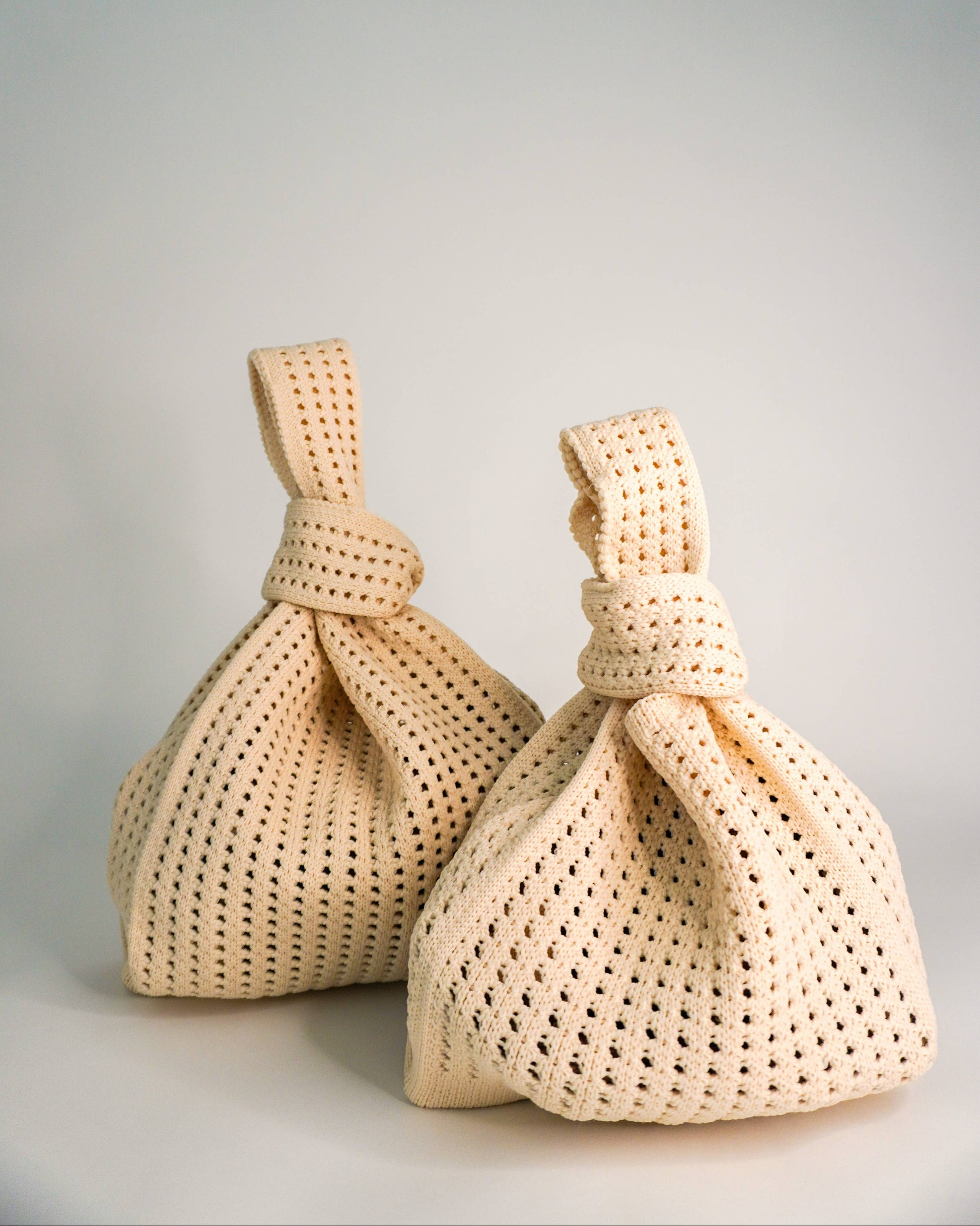 Two beige woven bags on a gray background