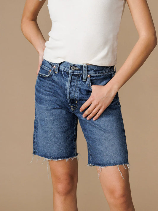 Close up front view of a model wearing the Edwin Sawyer Bermuda shorts in peck and a white tee with their thumb hooked in the front pocket standing in front of a neutral backdrop