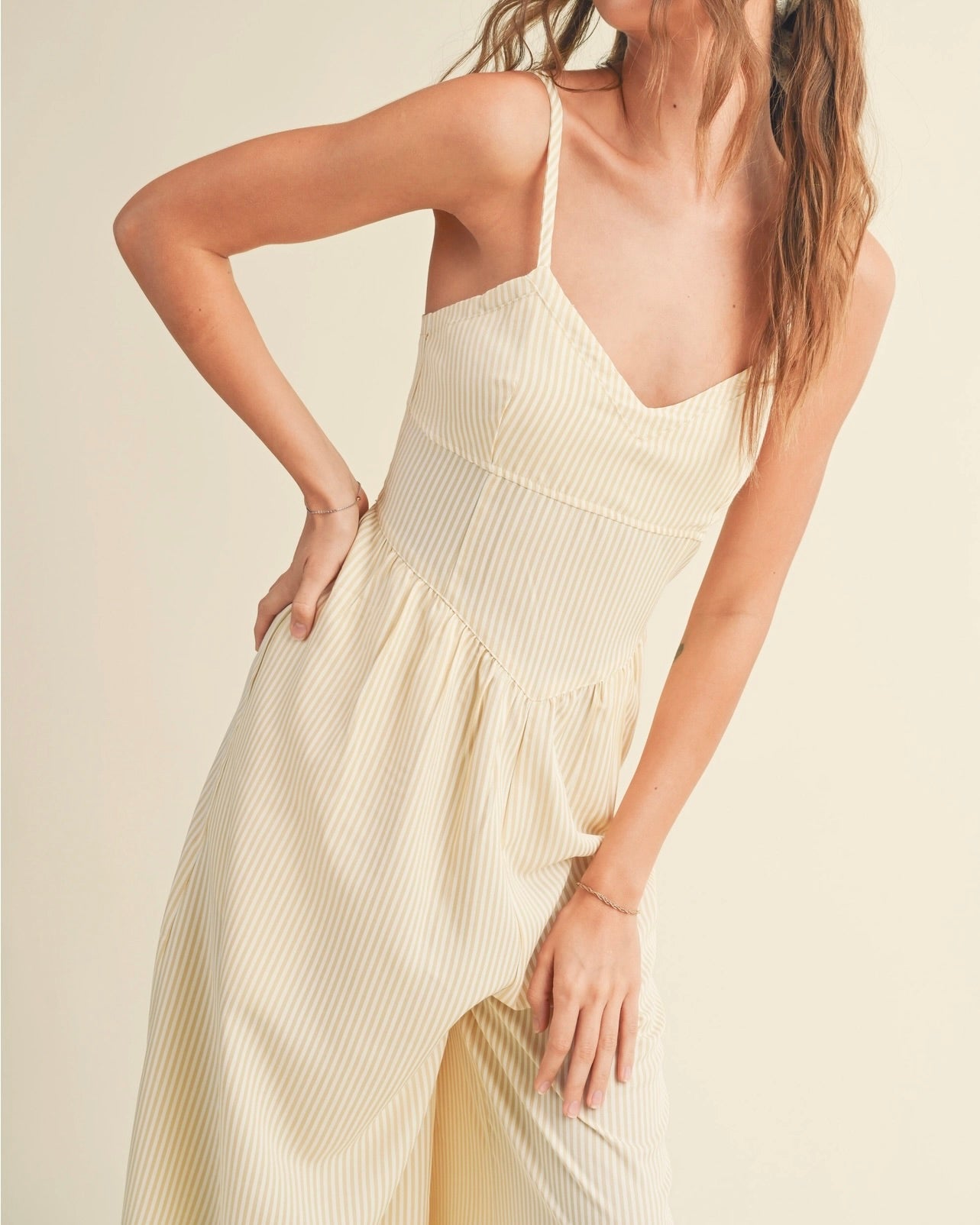 Model wearing Miou Muse Striped Jumpsuit on a beige background