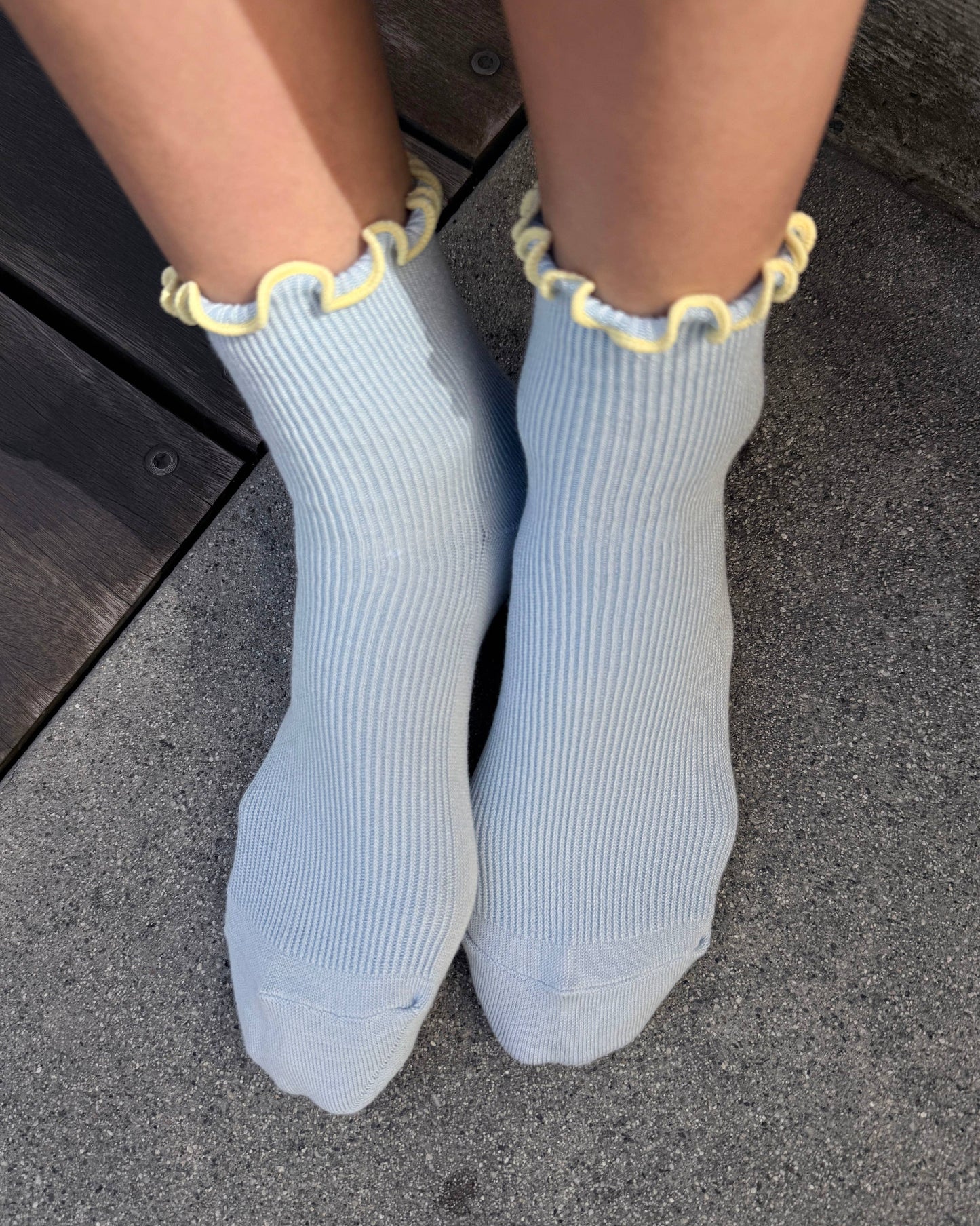 Light blue socks with yellow trim worn on a dark surface