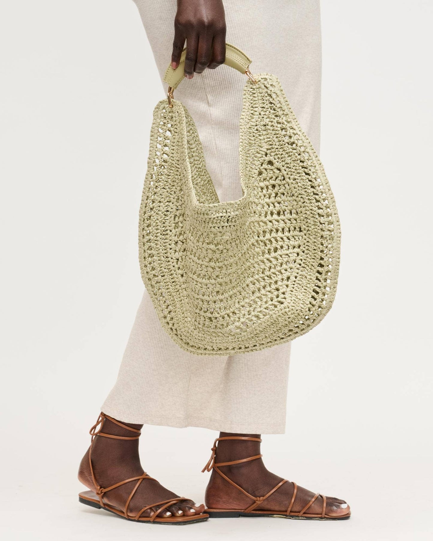 Person holding a woven handbag with a plain background