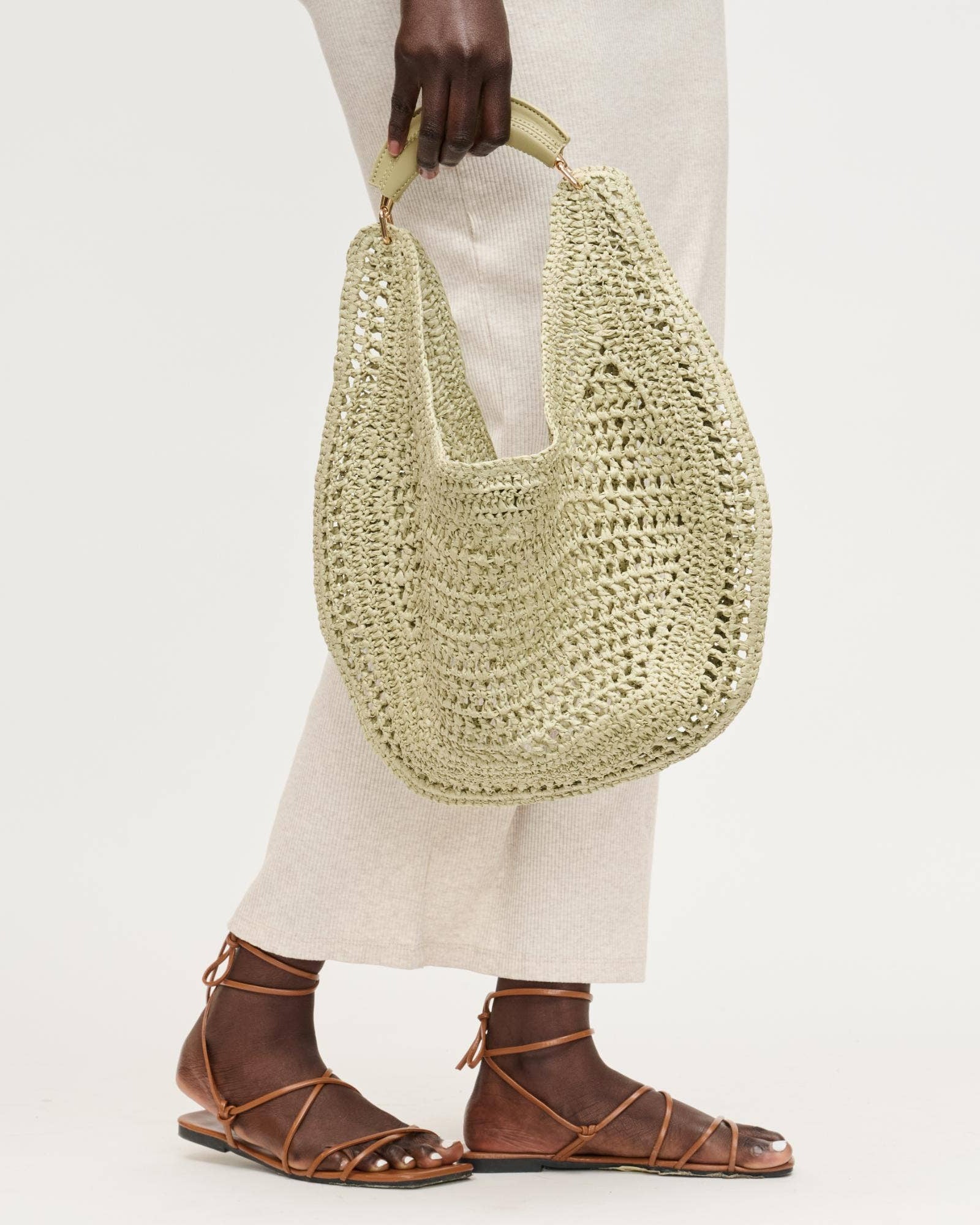 Person holding a woven handbag with a plain background