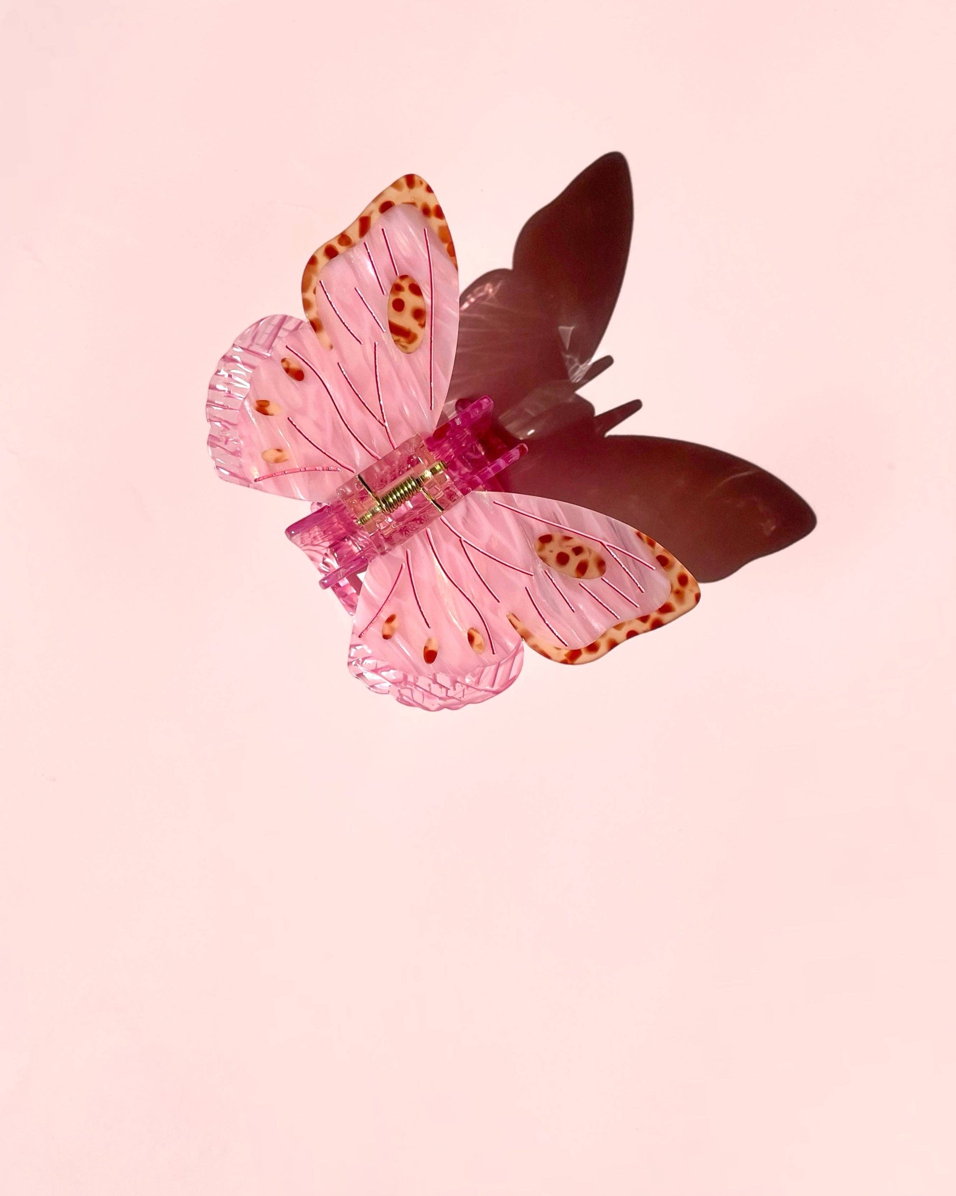 Butterfly-shaped hair clip on a pink background