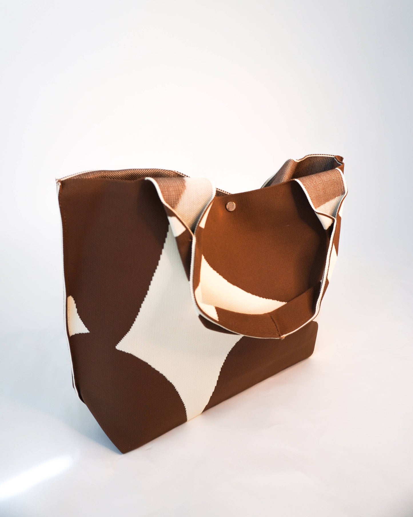 Brown and beige patterned handbag on a white background