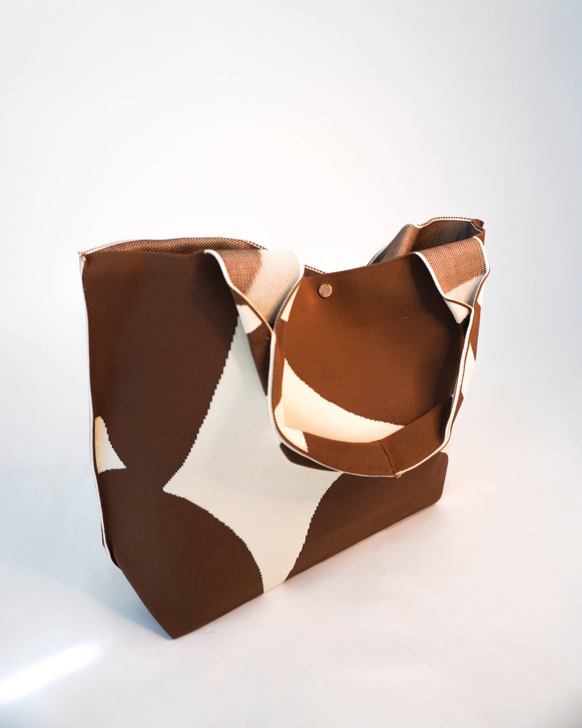 Brown and beige patterned handbag on a white background
