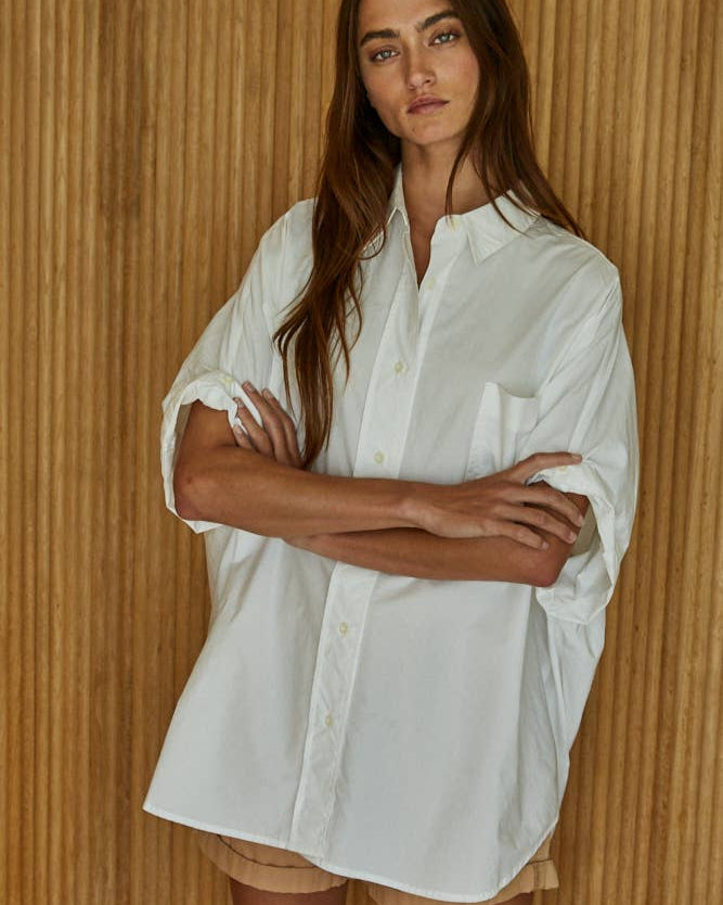 Woman wearing a white shirt against a wooden paneled wall