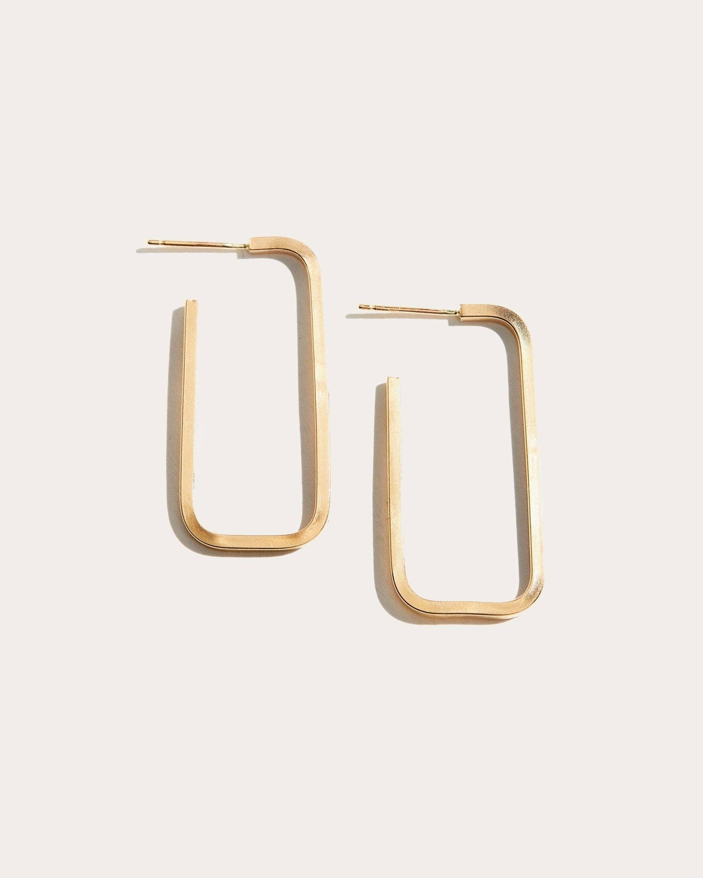 Gold hoop earrings on a light beige background
