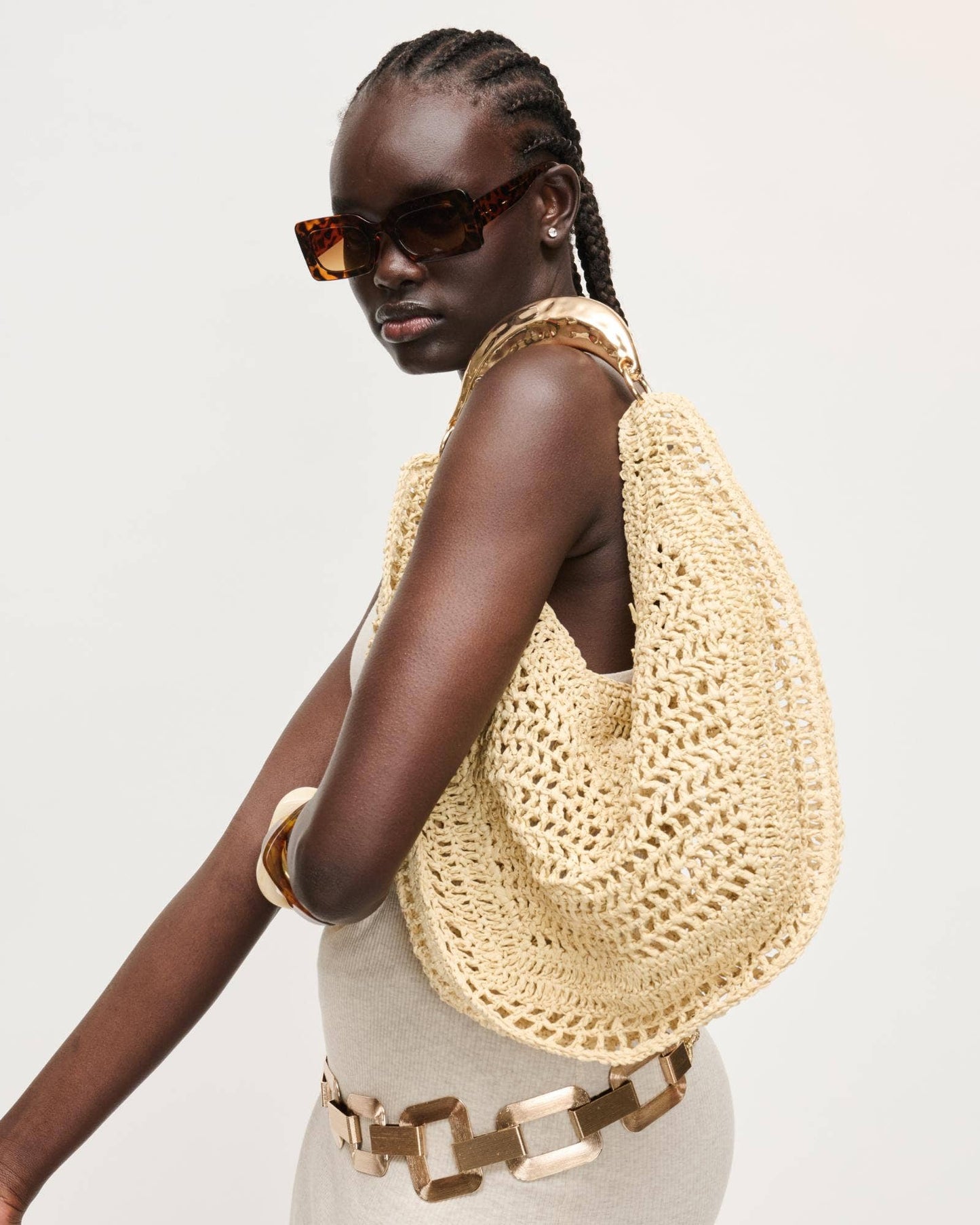 Woman wearing a beige crochet bag on a light gray background