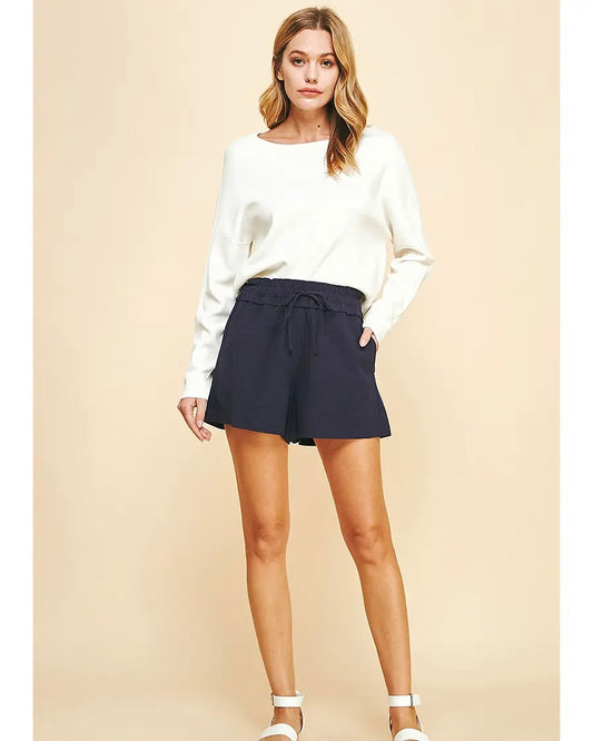 Model Wearing PINCH Woven Shorts wearing a white long sleeve on a brown background