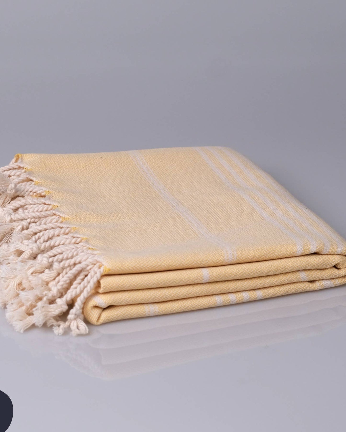 Folded yellow towel with white stripes and tassels on a gray background, featuring the Kallbadon brand.