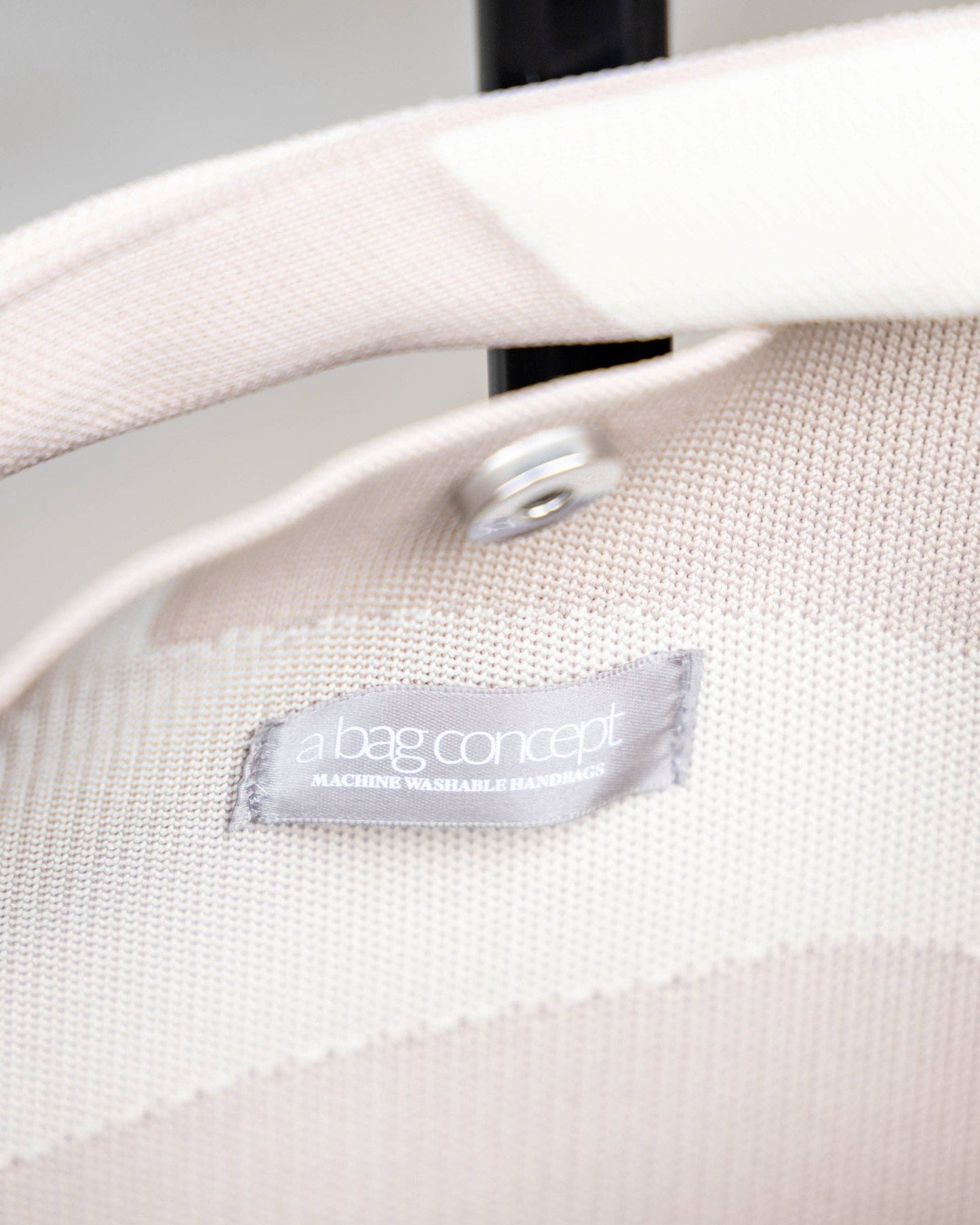 Close-up of a beige bag with a visible brand label on a neutral background