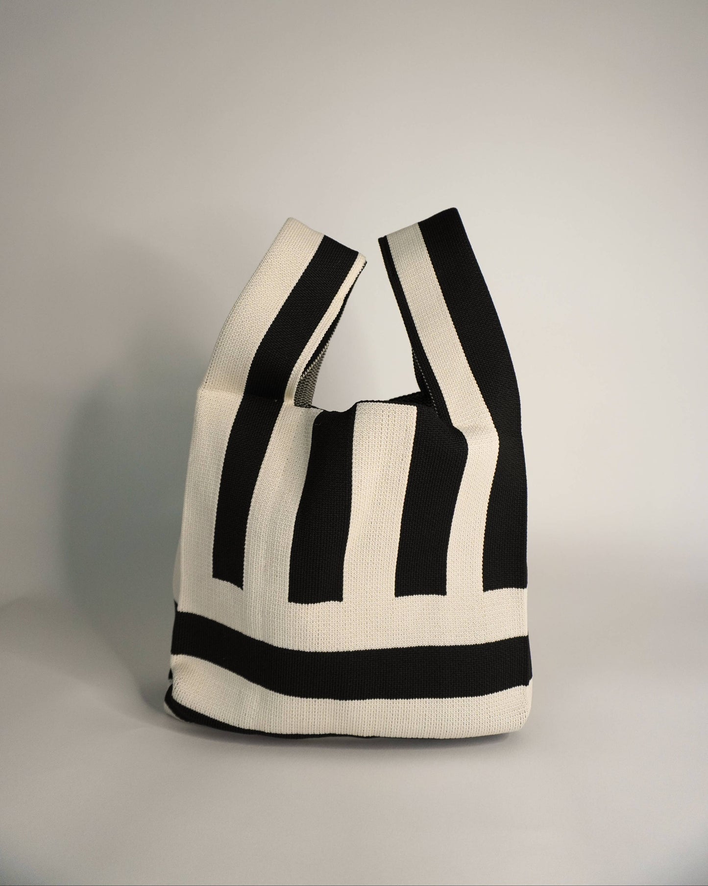 Black and white striped tote bag on a gray background