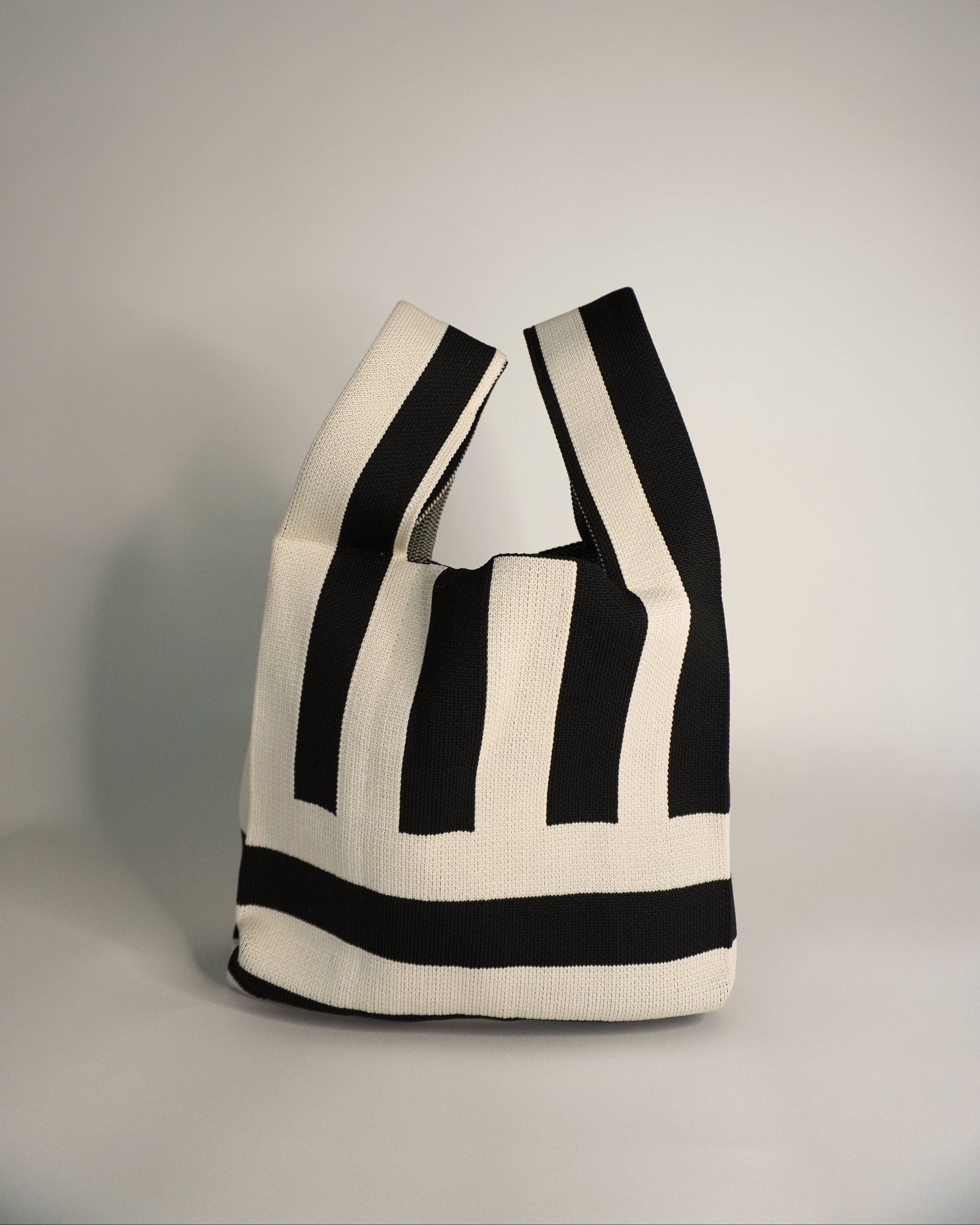 Black and white striped tote bag on a gray background