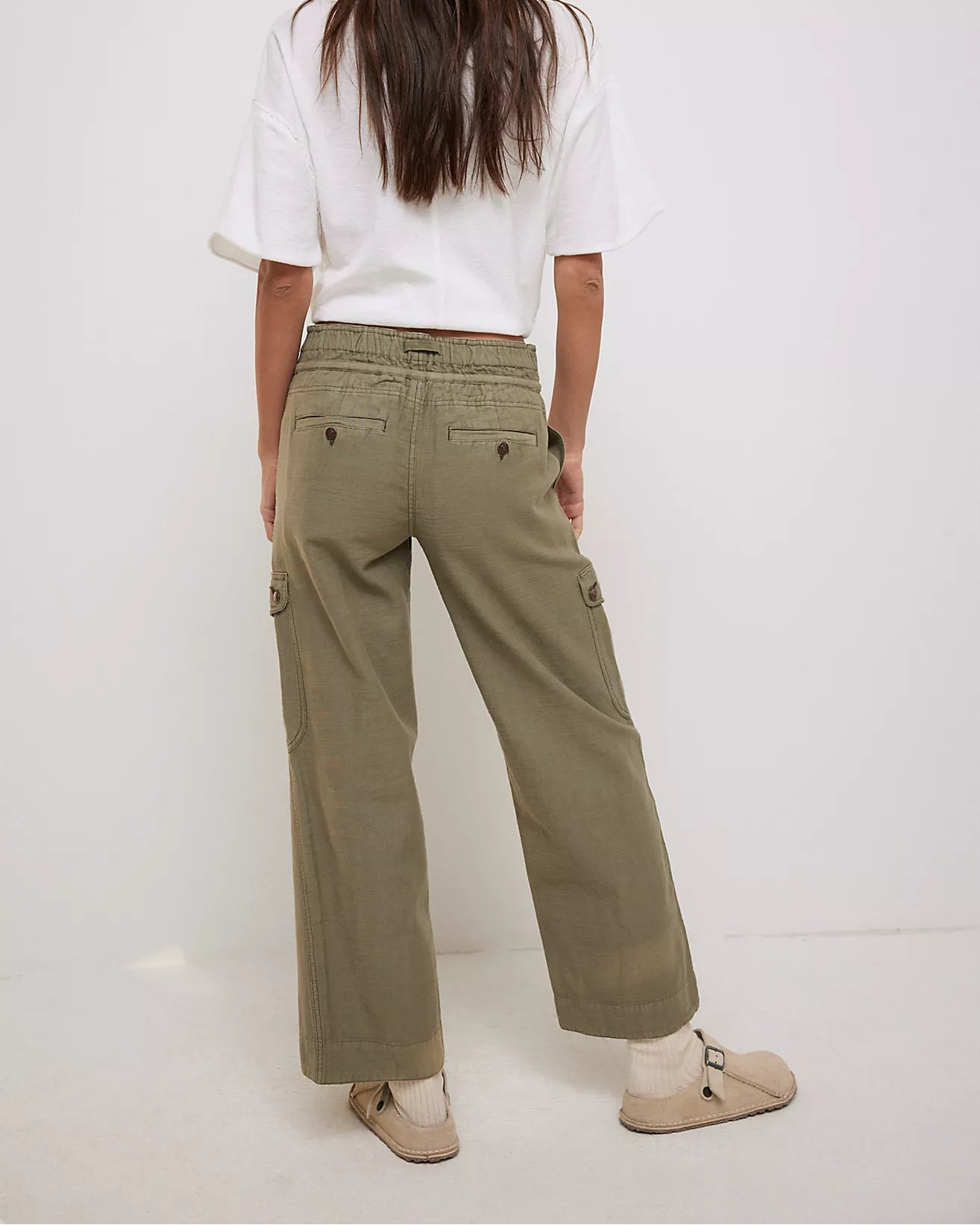 Person wearing a white shirt and green pants on a white background