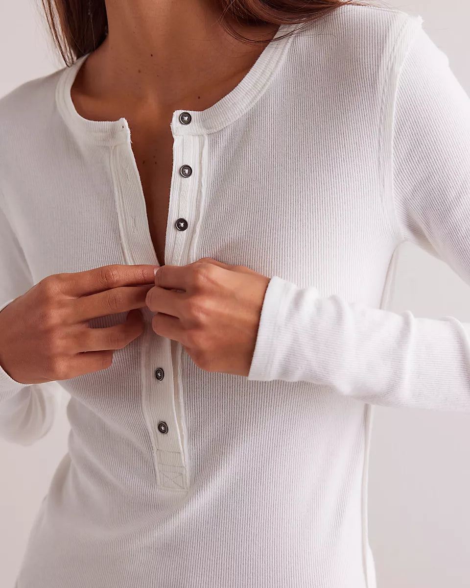 White long-sleeve shirt with buttons being fastened on a plain background