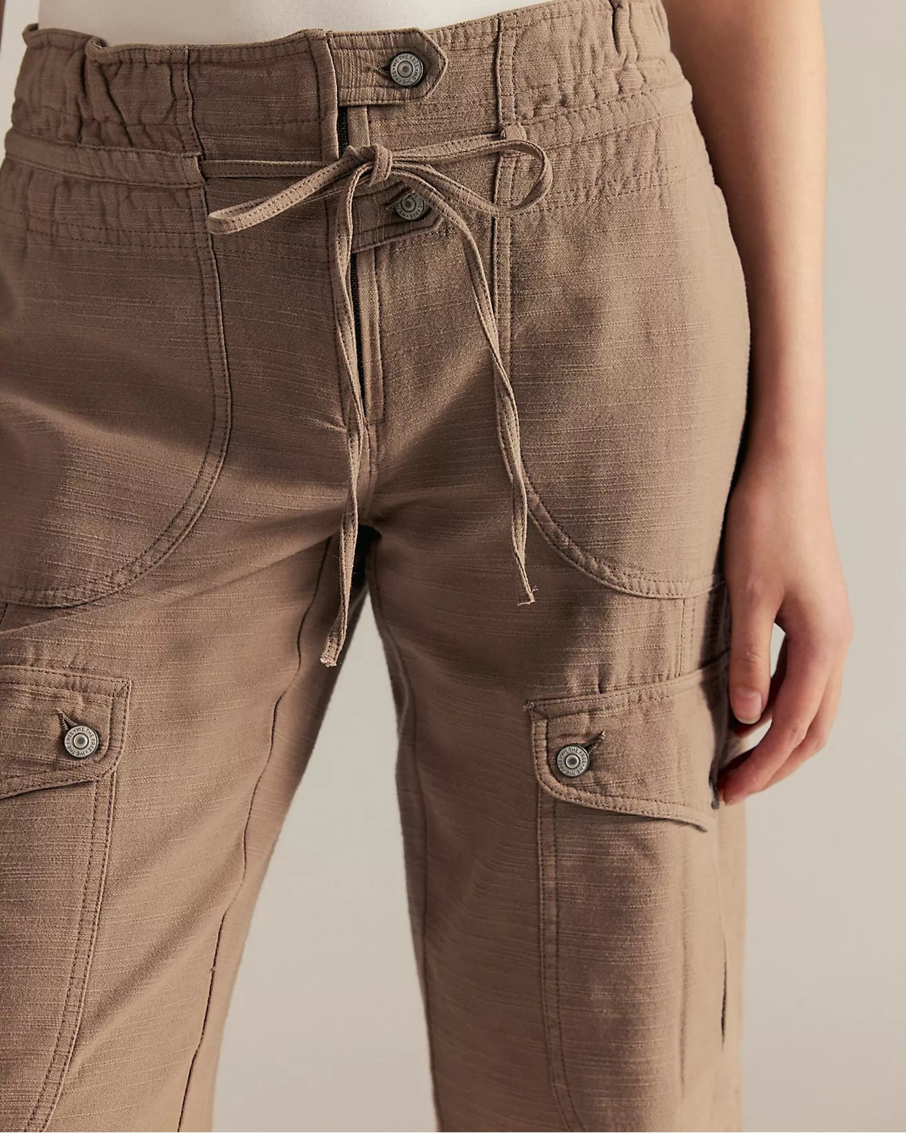 Brown cargo pants with a tie waist on a neutral background