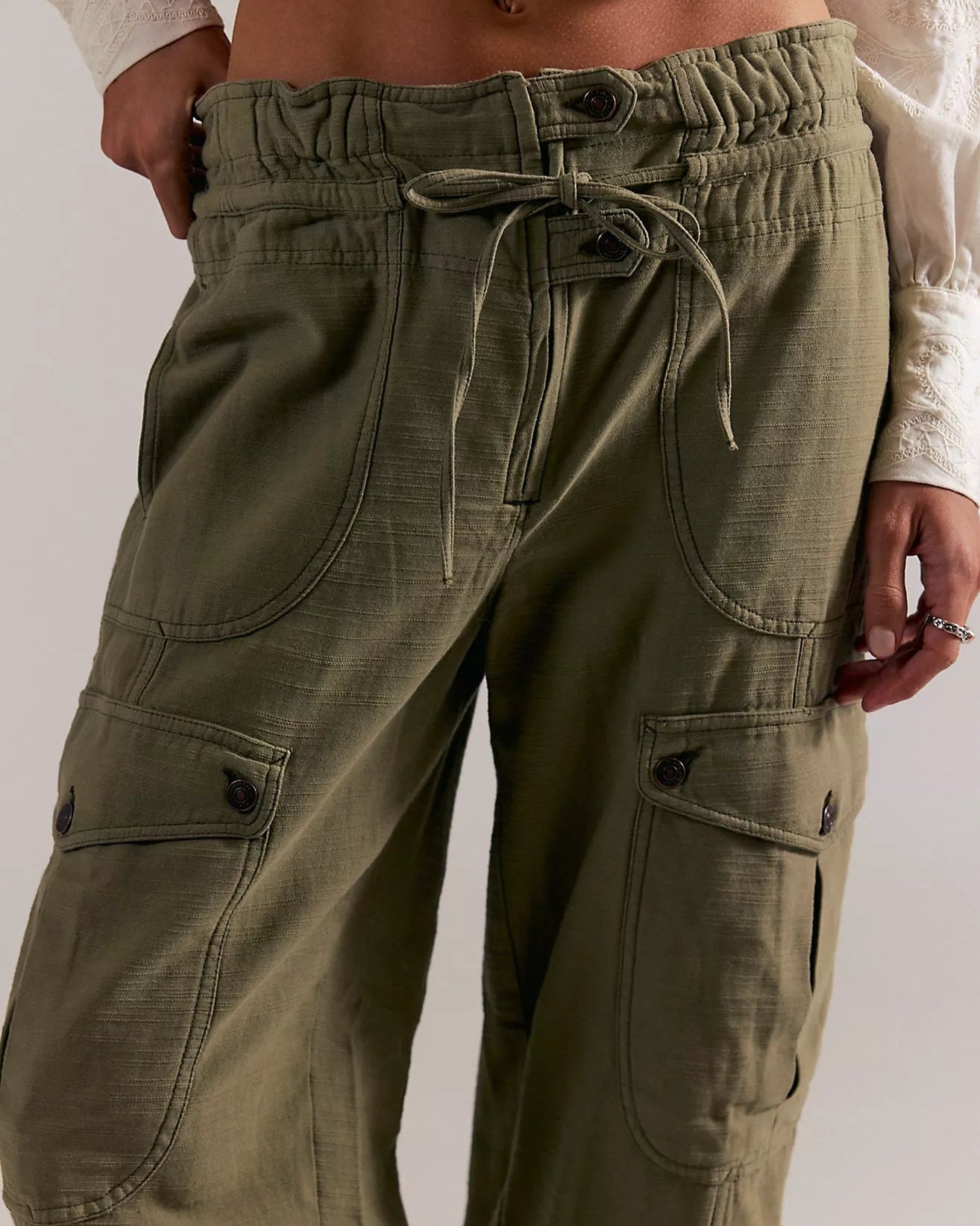 Green cargo pants with a drawstring waist on a plain background