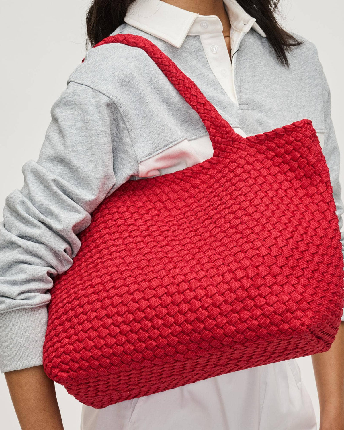 Person holding a red woven bag against a plain background