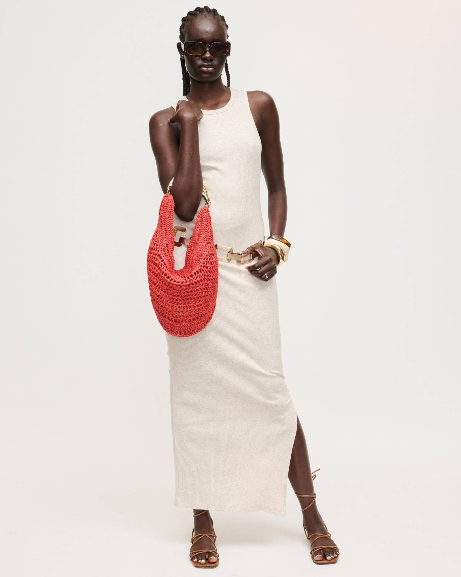 Woman holding a red woven bag against a white background