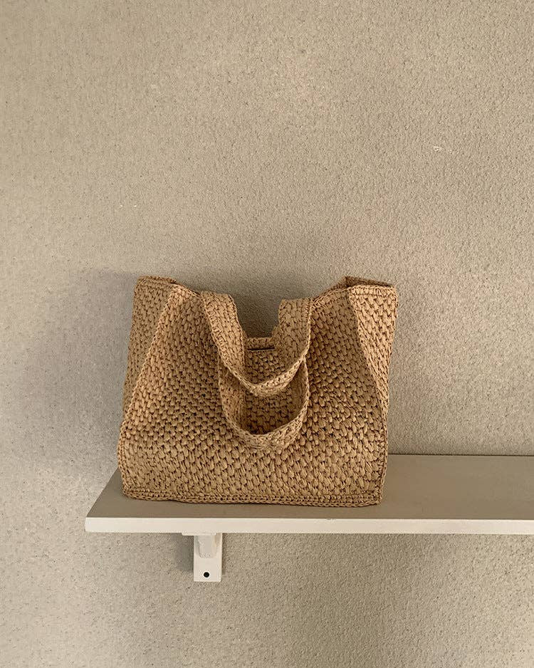Woven brown bag on a white shelf against a beige wall