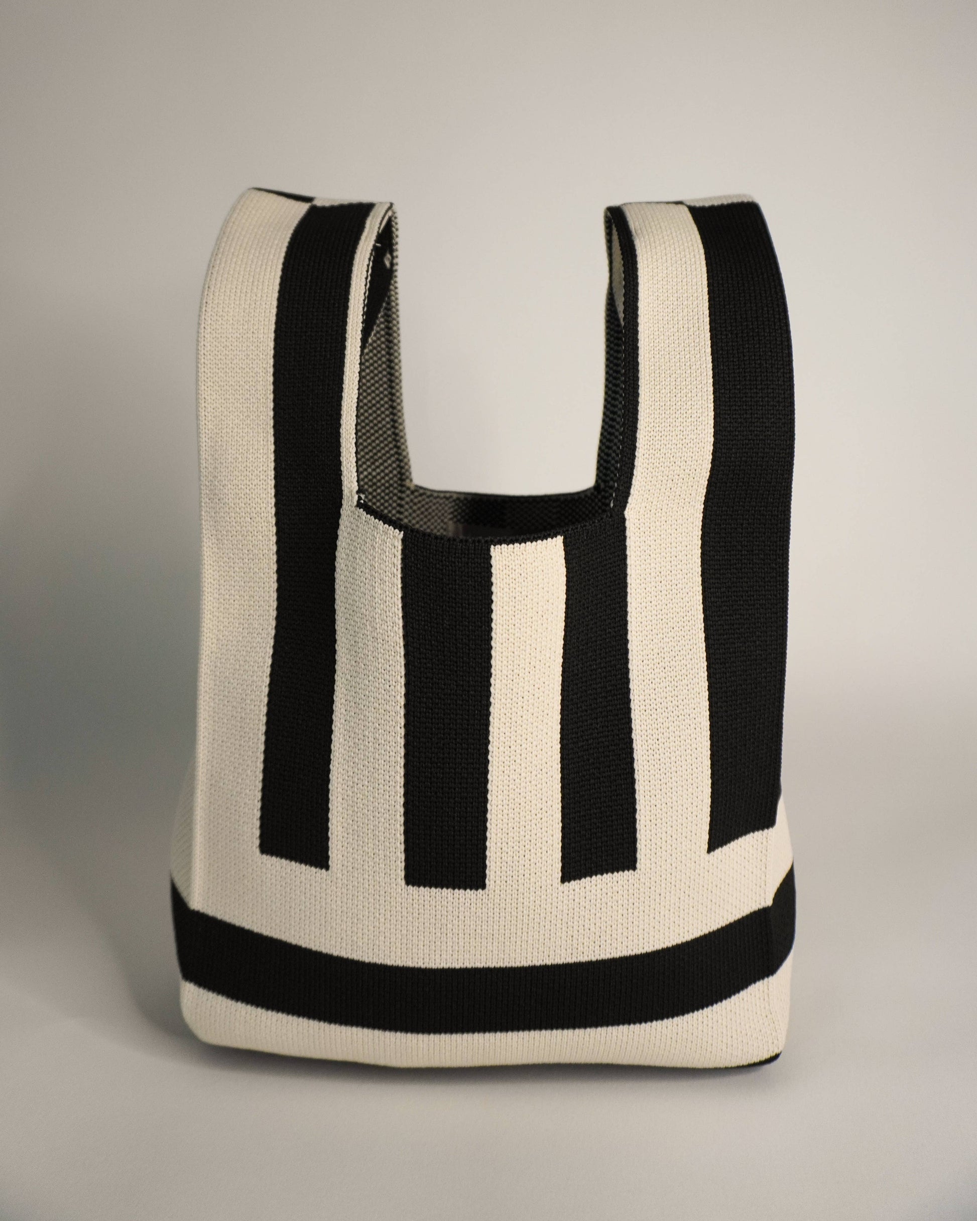 Black and white striped tote bag on a gray background