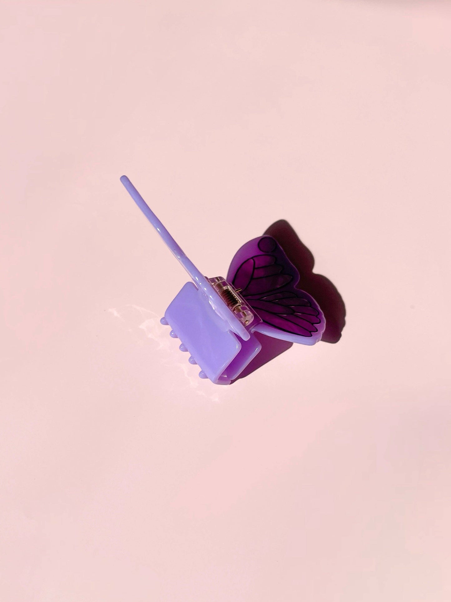Butterfly-shaped hair clip on a pink background