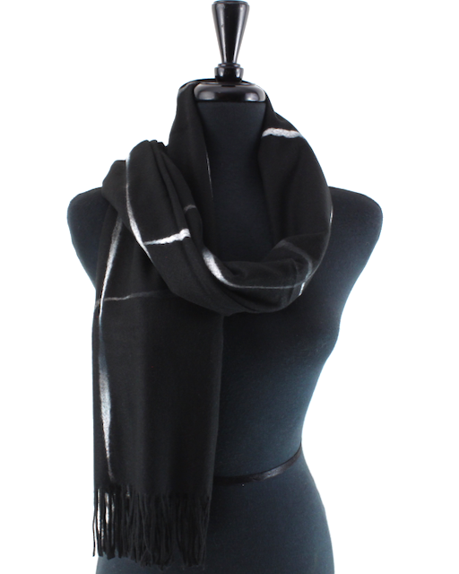 A black scarf with white stripe details and fringe, draped on a black mannequin torso against a white background.