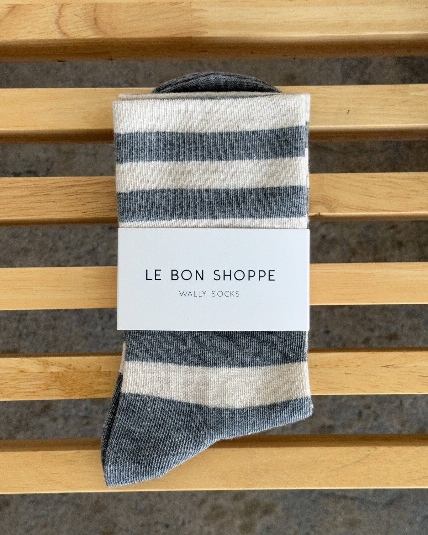 Striped sock with 'Le Bon Shoppe' label on a wooden slat background